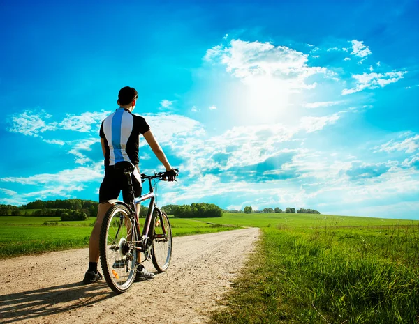 Hombre con una bicicleta en hermoso fondo de la naturaleza — Foto de Stock