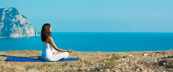 Frau macht Yoga in der Nähe des Ozeans — Stockfoto