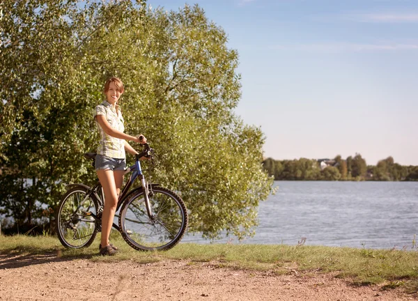 Mujer con una bicicleta en hermoso fondo de la naturaleza —  Fotos de Stock