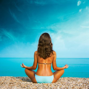 Denizde yoga yapan kadın.