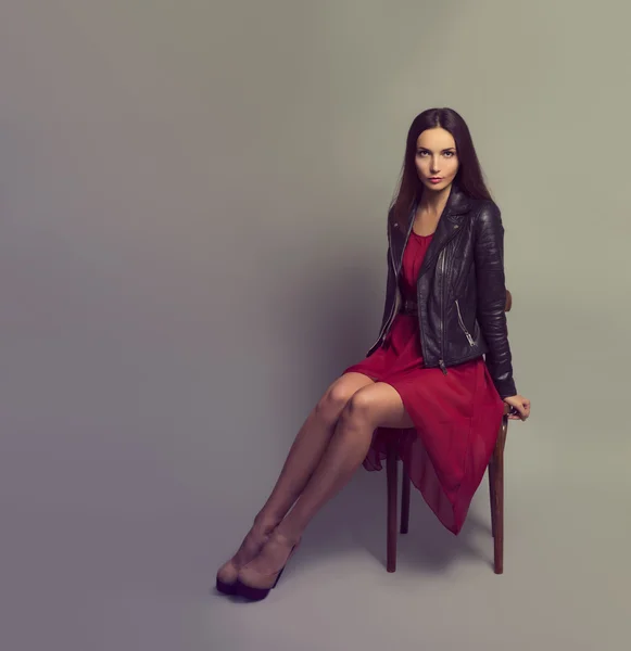 Mulher morena em vestido vermelho Sentado em uma cadeira — Fotografia de Stock