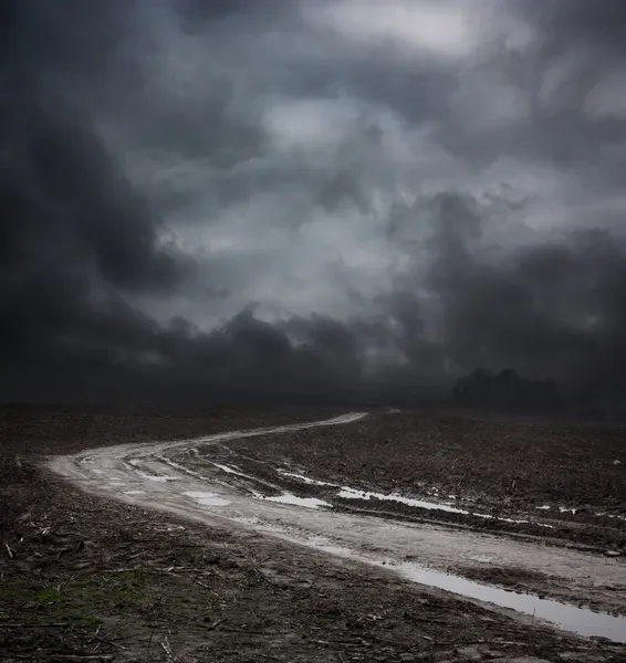 Mörka landskap med smutsiga road och lynnig sky — Stockfoto