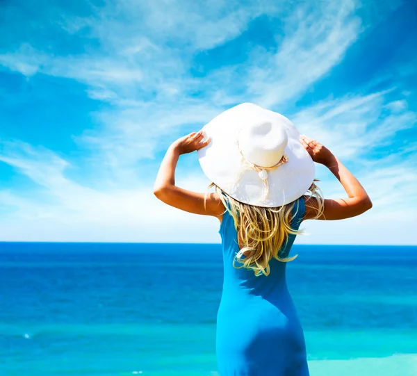 Kvinna i blå klänning och hatt till sjöss. bakifrån. — Zdjęcie stockowe