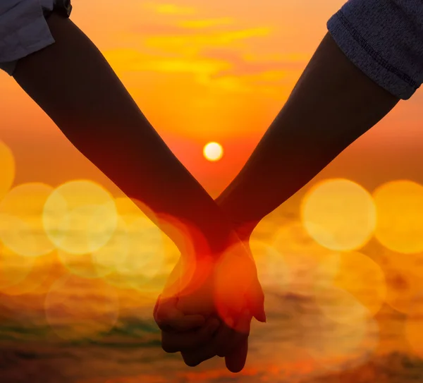 Casal segurando as mãos no pôr do sol do mar — Fotografia de Stock