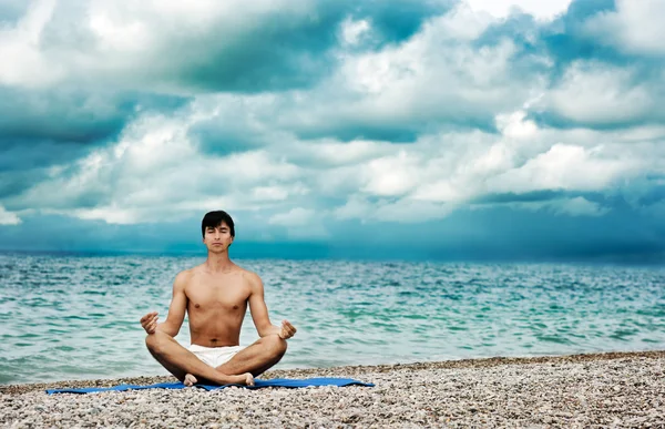 Uomo che fa yoga vicino al mare — Foto Stock