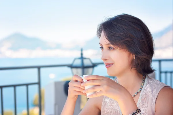 Young Woman Drinking Coffee at Cafe Terrace