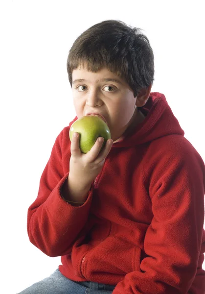 Child biting a green apple with red shirt — Stock Photo, Image