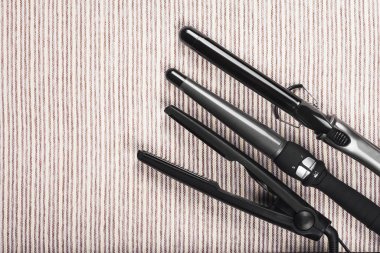 Gri çizgili arka planda çeşitli saç düzleştirici araçlar