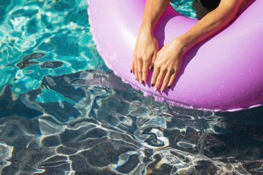 Kadın elleri yüzme havuzundaki yüzme yüzüğünün üstünde.