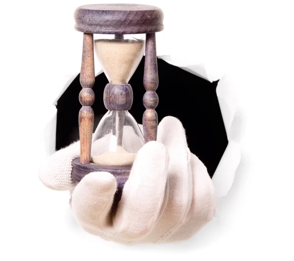 Man med handskar håller sand klocka i fingret genom ett hål — Stockfoto