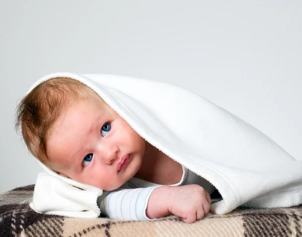 Baby boy holds raised head with blanket over head — Stock Photo, Image