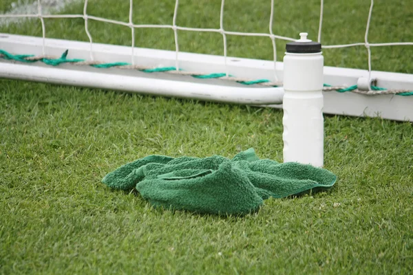 Fles en handdoek op het voetbalveld — Stockfoto