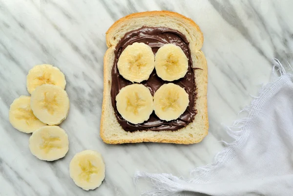 Bread with chocolate cream and slices of banana — Stock Photo, Image