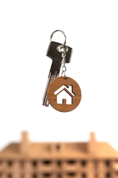 房地产概念。带有房屋形状钥匙链的钥匙与褐色房子模型的对比. — 图库照片