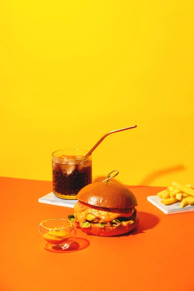 Великий бургер з картоплею фрі і соусом на яскраво помаранчевому і жовтому тлі. Американська кухня швидкого харчування. — стокове фото