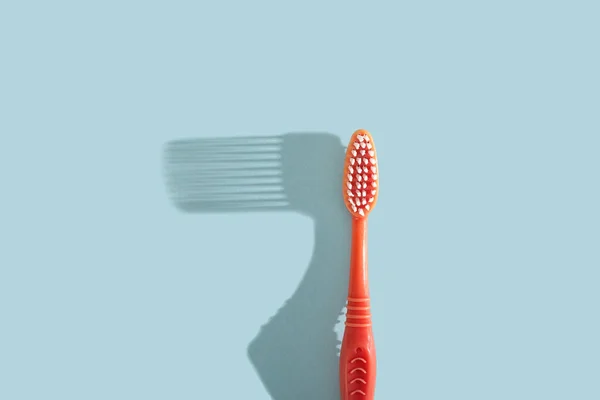 Pink toothbrush on blue background with hard shadow. Dental care concept. — Stock Photo, Image