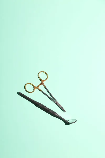 Ferramentas de metal dentista com espelho sobre fundo de hortelã verde. Minimalismo. Conceito de assistência odontológica. — Fotografia de Stock