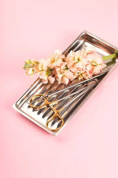 Outils dentaires sur plateau en métal avec des fleurs sur fond rose. Concept d'art dentaire. — Photo