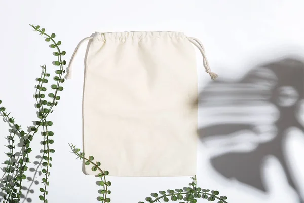 La bolsa Eco reutilizable se burla de la compra de cero residuos entre hojas verdes y sombras. Mínimo plano lay. — Foto de Stock