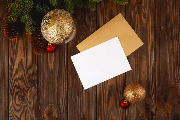 Макет рождественской открытки. Белая минимальная пустая открытка на деревянном столе с праздничными украшениями и ремесленными письмами. — стоковое фото