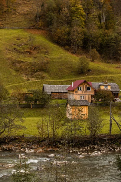 Осінній гірський пейзаж з жовтою травою та сільськими дерев'яними будинками. Природа села — стокове фото