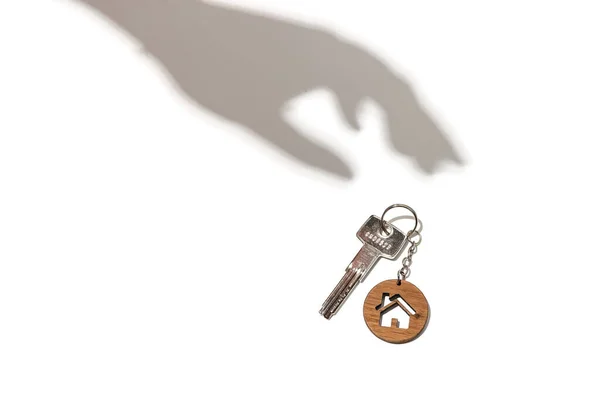 房地产概念。带有白色背景上的手工阴影的房子形钥匙链的钥匙. — 图库照片