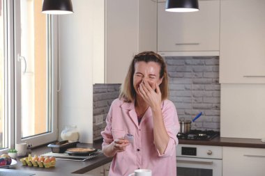 Otantik bir kadın elinde çay, elinde makarna ve fincanla gülüyor..