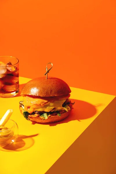 Big burger z frytkami i sosem na jasnym pomarańczowym i żółtym tle. American Fast Food kuchni. — Zdjęcie stockowe
