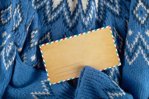 Enveloppe artisanale de Noël maquillée sur pull bleu. Personne à plat. — Photo