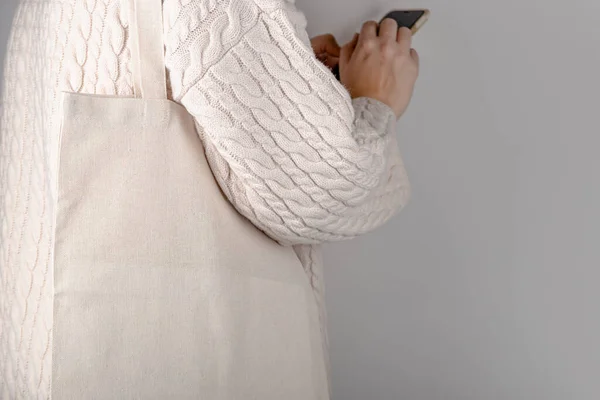 Туалетний пакетик накидається на плече жінки в светрі. Макет еко сумки — стокове фото