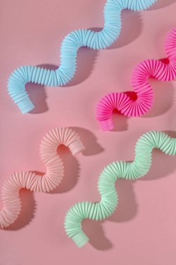 Pembe arka planda gölgesi olan kavisli pembe nane anti-stres tüpü oyuncağı. Akıllı çocuk oyuncağı.