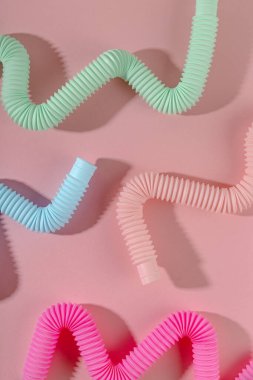 Pembe arka planda gölgesi olan kavisli pembe nane anti-stres tüpü oyuncağı. Akıllı çocuk oyuncağı..