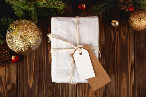 크리스마스 선물 Tag 흉내내기. 축제 장식품들이 있는 나무 탁자 위에 놓여 있는 가장 작은 흰색 선물 상자. — 스톡 사진