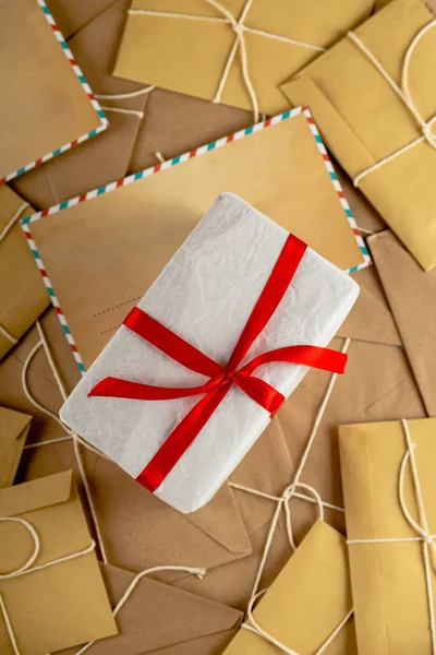 White minimal Christmas gift on lots of vintage craft envelopes and Santa letters. — Stock Photo, Image