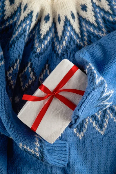 蓝色毛衣上印有白色的简约圣诞礼物和红色缎带。没有人平躺在地上. — 图库照片