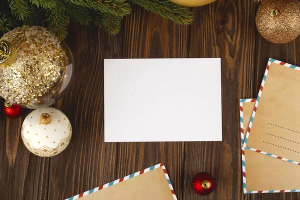 Tarjeta de Navidad maqueta. Postal blanca mínima vacía sobre mesa de madera con decoraciones festivas y cartas artesanales. —  Fotos de Stock