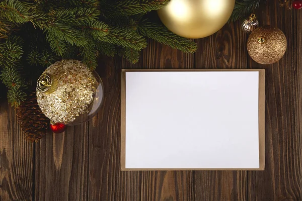 Макет рождественской открытки. Белая минимальная пустая открытка на деревянном столе с праздничными украшениями и ремесленным конвертом. — стоковое фото