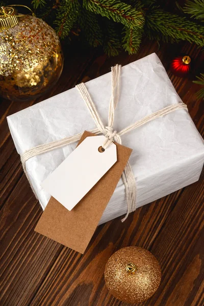 Christmas Gift Tag mockup. White minimal gift box on wooden table with festive decorations. — Stock Photo, Image