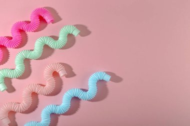 Pembe arka planda gölgesi olan kavisli pembe nane anti-stres tüpü oyuncağı. Zeki çocuk oyuncağı. Kopyalama alanı
