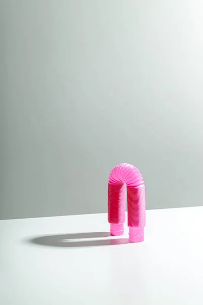 Giocattolo rosa antistress pop tube a forma di arco su sfondo chiaro con ombra. Giocattolo per bambini luminoso. Copia spazio — Foto Stock