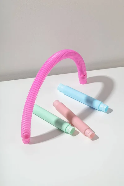 Jouet tube anti-stress pop menthe rose bleu sous tuyau rose en forme d'arche avec ombre sur fond clair. Composition en forme de cœur. Jouet enfant lumineux — Photo
