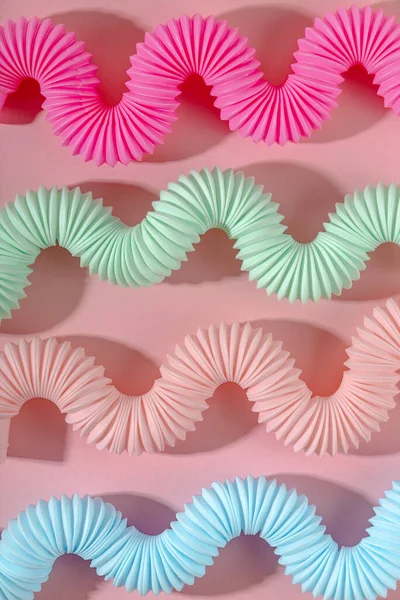 Gebogen roze blauwe munt antistress pop tube speelgoed met schaduw op roze achtergrond. Helder kinderspeelgoed. Behang — Stockfoto