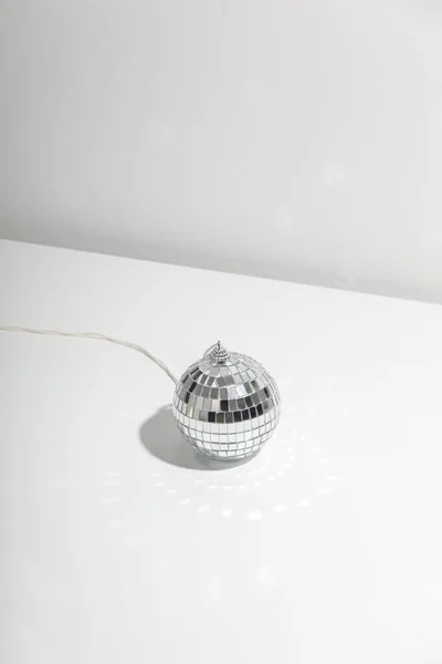 Balle disco grise repose sur fond argenté avec ombre. — Photo