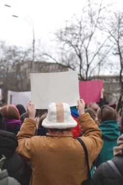 Elinde feminist protestoların arka planına karşı afiş tutan bir kadın. Boşluğu kopyala.