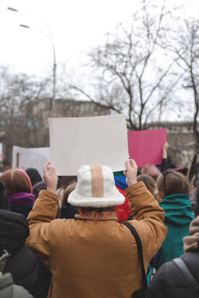 Женщина держит плакат в руке на фоне феминистского протеста. Копирование пространства.