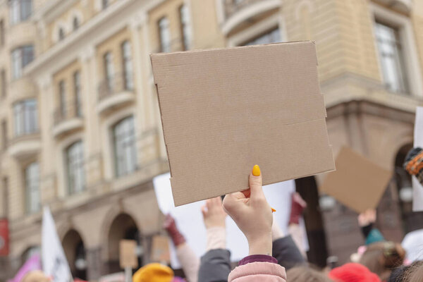 Женщина держит плакат в руке на фоне феминистского протеста. Копирование пространства.