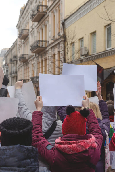 Женщина держит плакат в руке на фоне феминистского протеста. Копирование пространства.