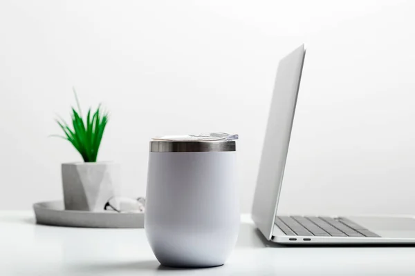 Taça térmica branca simular no moderno local de trabalho elegante com laptop. Mockup Copa. — Fotografia de Stock