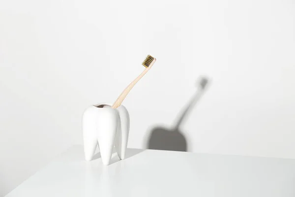 Escova de dentes de bambu ecológica em forma de dente. Consumo consciente e conceito de assistência odontológica. — Fotografia de Stock