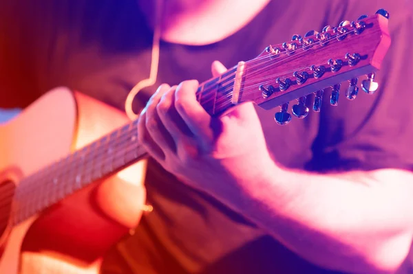 Parlak bir sahne ışığında gitaristin elindeki on iki telli gitarı kapat..